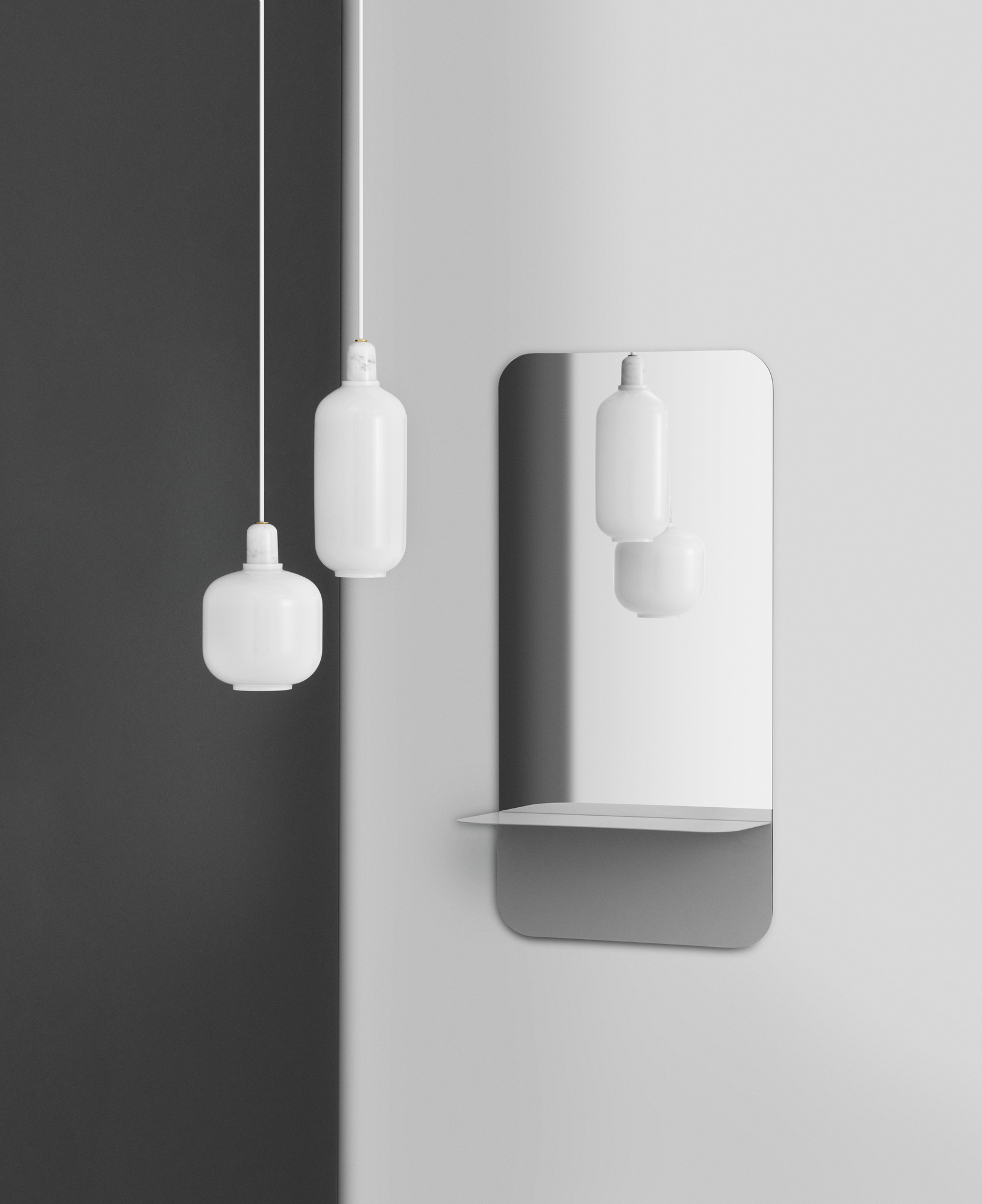 Zwei weiße Amp Lamp Pendelleuchten von Normann Copenhagen vor einer grauen Wand und Spiegel.