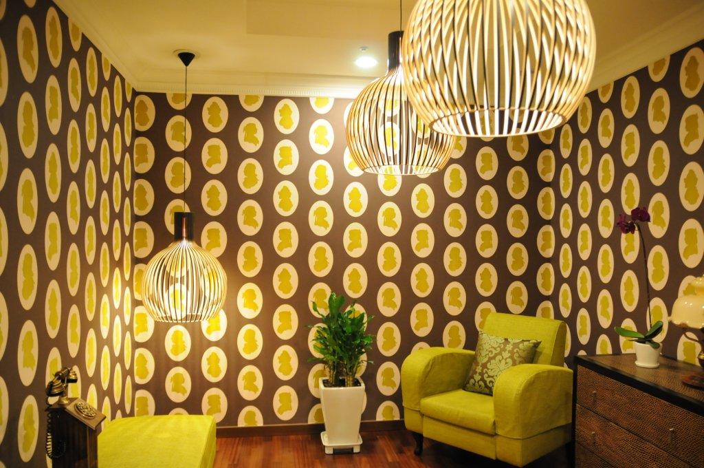 Nahaufnahme von drei Octo Pendelleuchten von Secto Design, die in einem Wohnzimmer mit Mustertapete hängen.
