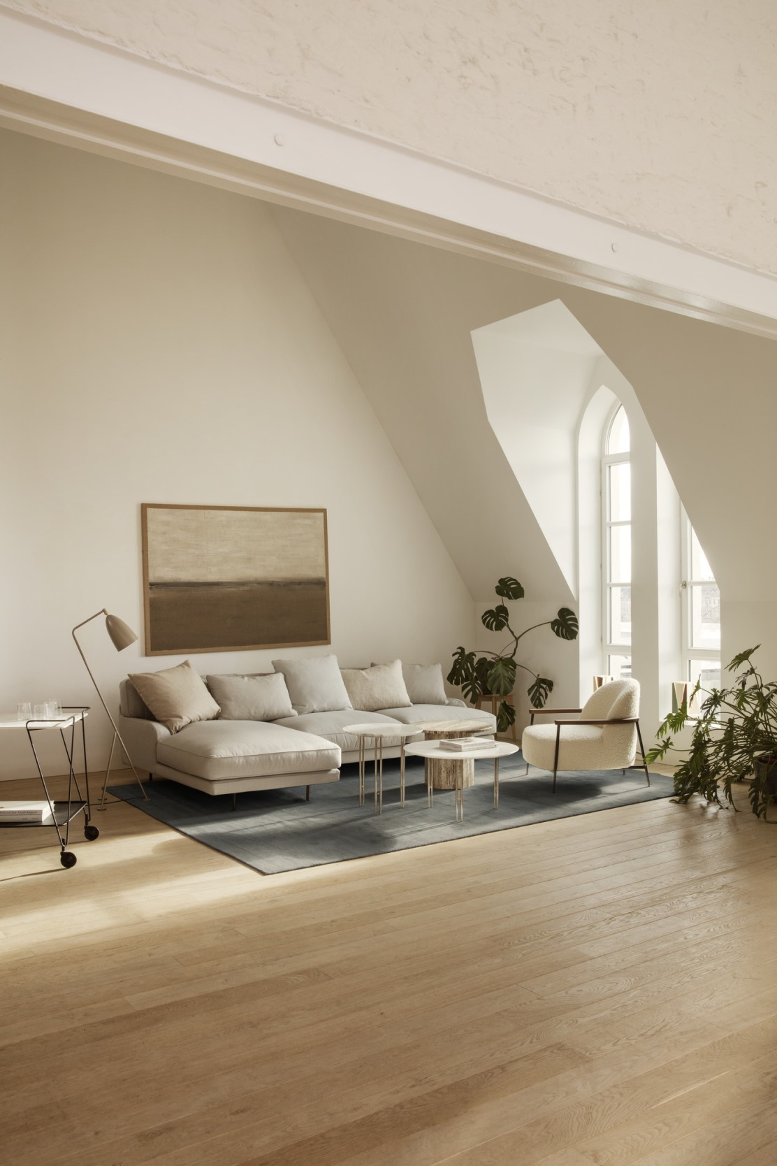Heller Wohnraum mit Gubi Couchtisch Epic Coffee Table, Sofa, Sessel und Pflanzen.