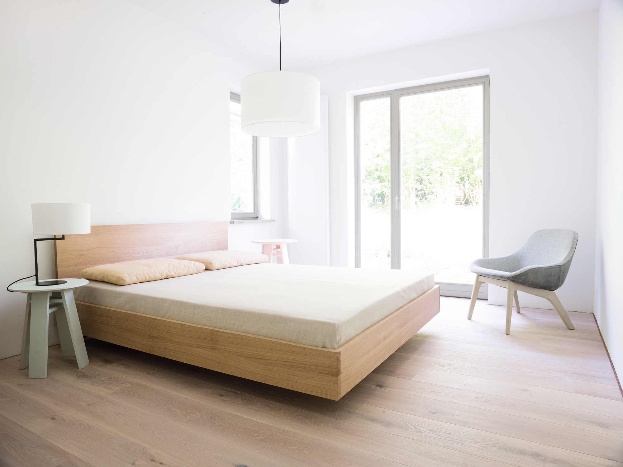 Schlafzimmer mit Bett, Stuhl und Neat Noon Tischleuchte in Weiß, modernes Design.