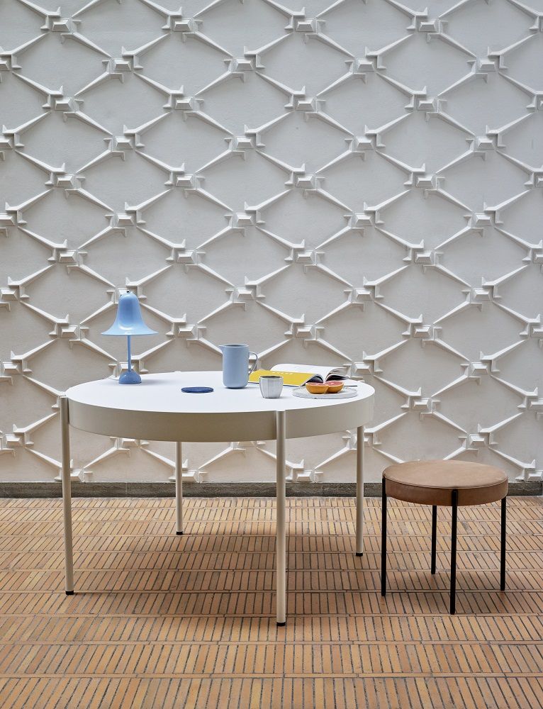 Pantop Tischleuchte in Hellblau auf einem weißen Tisch mit Dekoration, minimalistisches Design für Wohnräume.