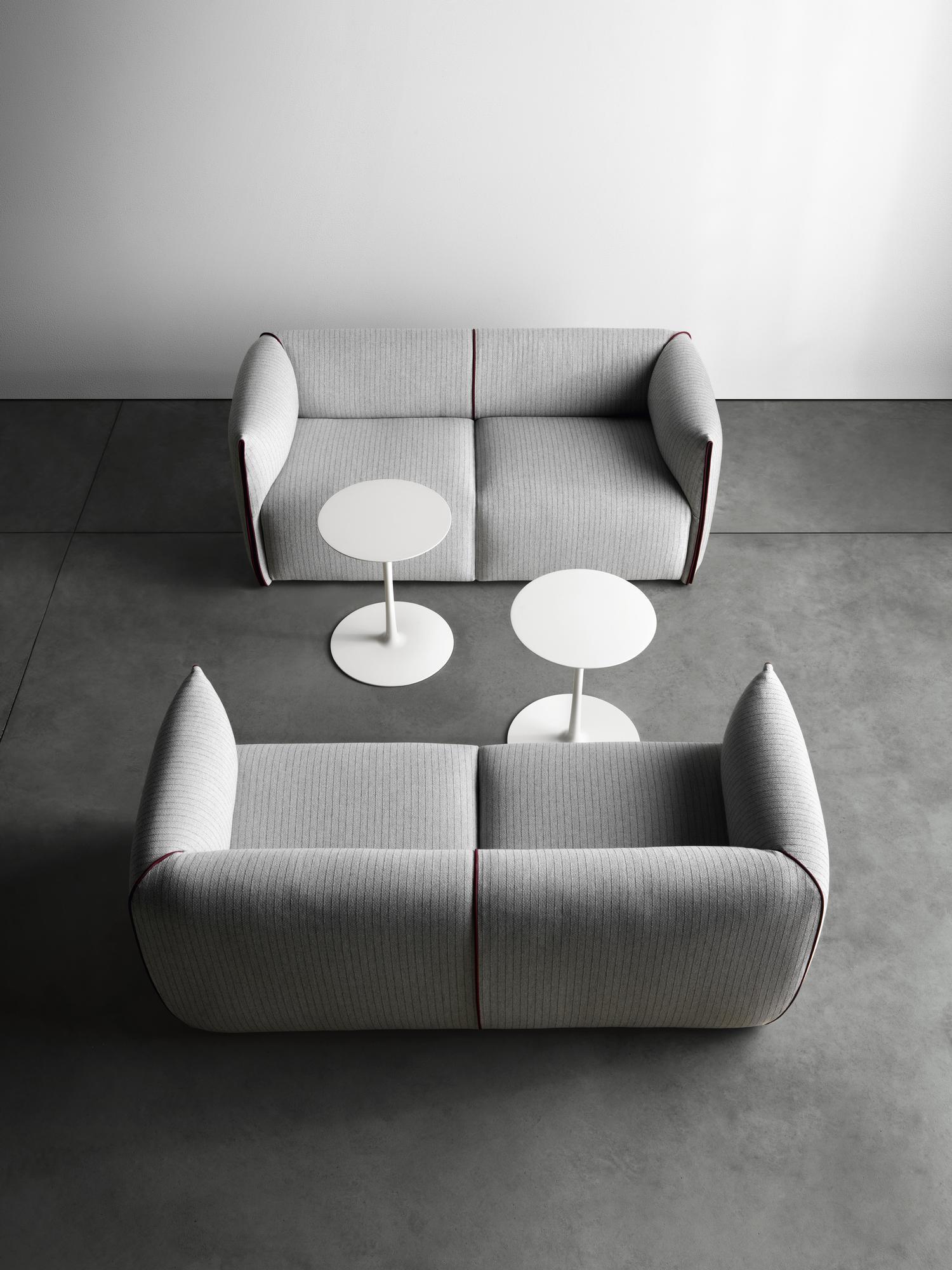 Zwei graue Mia Sofas von MDF Italia mit zwei weißen Tischen auf grauem Untergrund.
