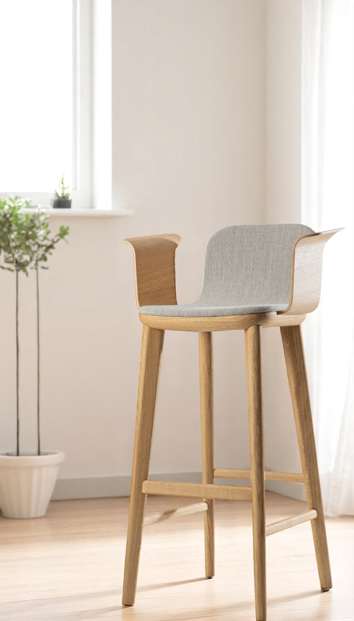 Aeon Comfort Barstool Barhocker mit Armlehnen, helles Holzgestell und grau gepolsterter Sitzfläche vor Fenster.