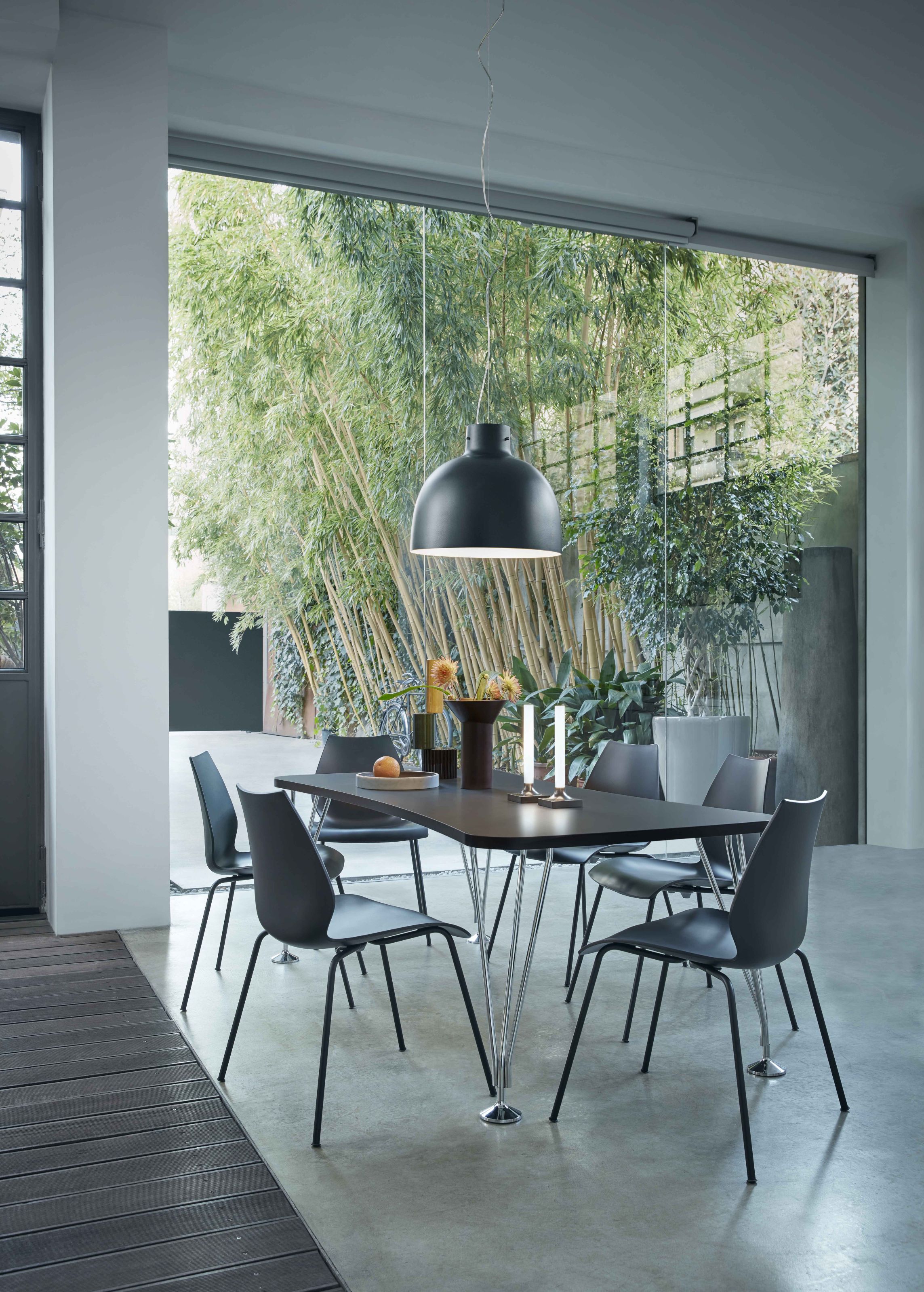 Bellissima Pendelleuchte in Grün über Esstisch mit Stühlen und Dekoration im modernen Esszimmer.