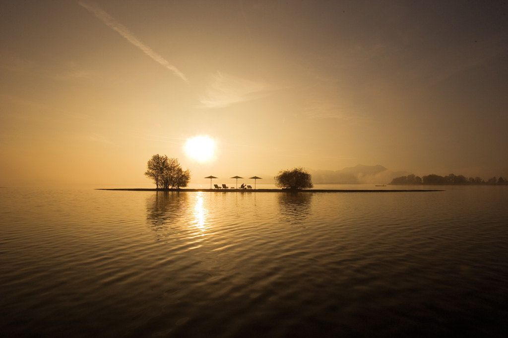 Weishäupl Sonnenschirme am Seeufer bei Sonnenaufgang, hochwertige Outdoor-Sonnenschirme für entspannte Stunden im Freien.