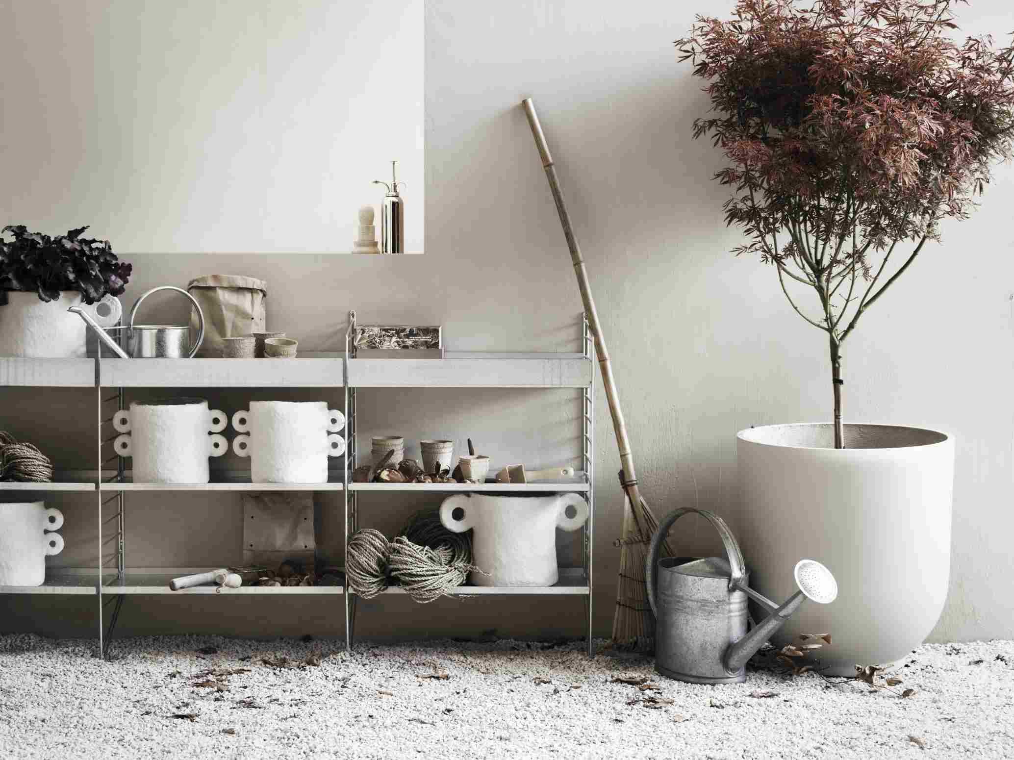 String Outdoor Regalsystem mit Gartenzubehör und Ahornbaum im Topf, modernes Design für den Garten.