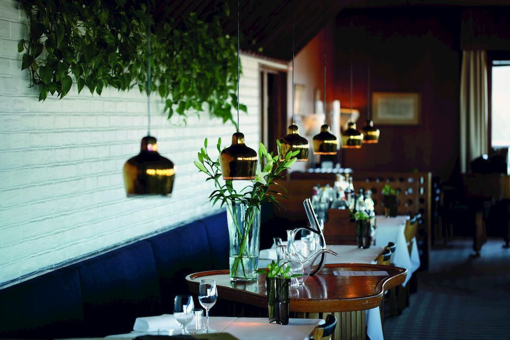 A330S Golden Bell Pendelleuchten von Artek über Tischen in einem eleganten Restaurant.