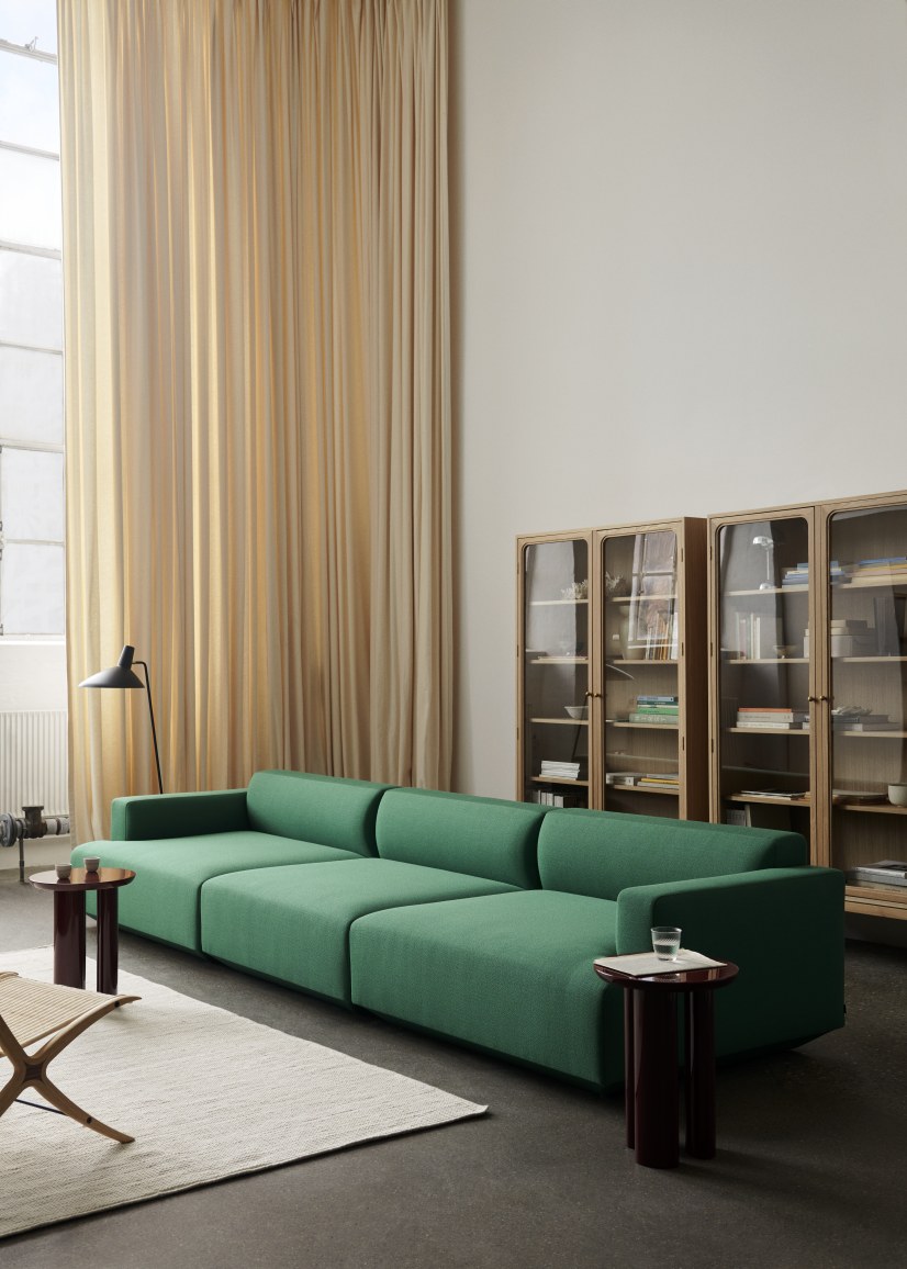 Wohnzimmer mit grünem Modulsofa, Beistelltischen, Teppich und drei AndTradition Trace SC88 Vitrinen aus Eiche.