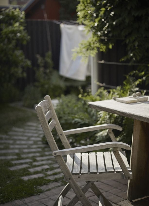 Selandia Armchair Outdoor Sessel von Skagerak by Fritz Hansen im Garten mit Tisch.