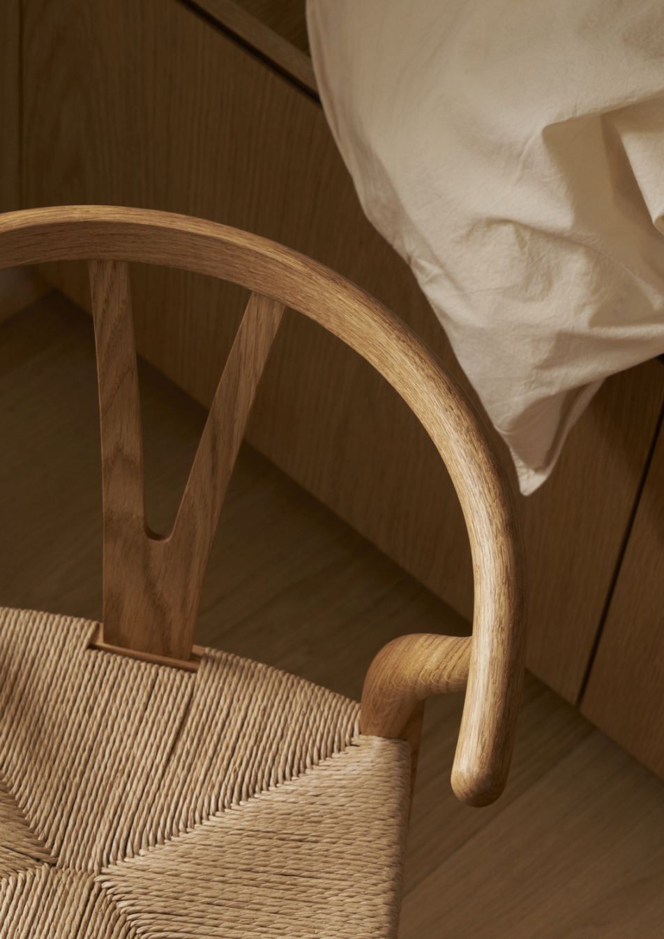 Detailaufnahme des CH24 Wishbone Stuhls von Carl Hansen, Holzrahmen und geflochtener Sitz.