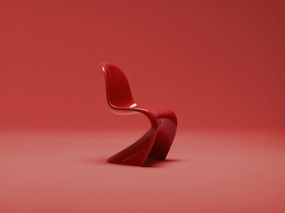 Roter Freischwinger Stuhl aus Kunststoff mit geschwungener Form vor rotem Hintergrund. Design Möbel für Wohnzimmer.