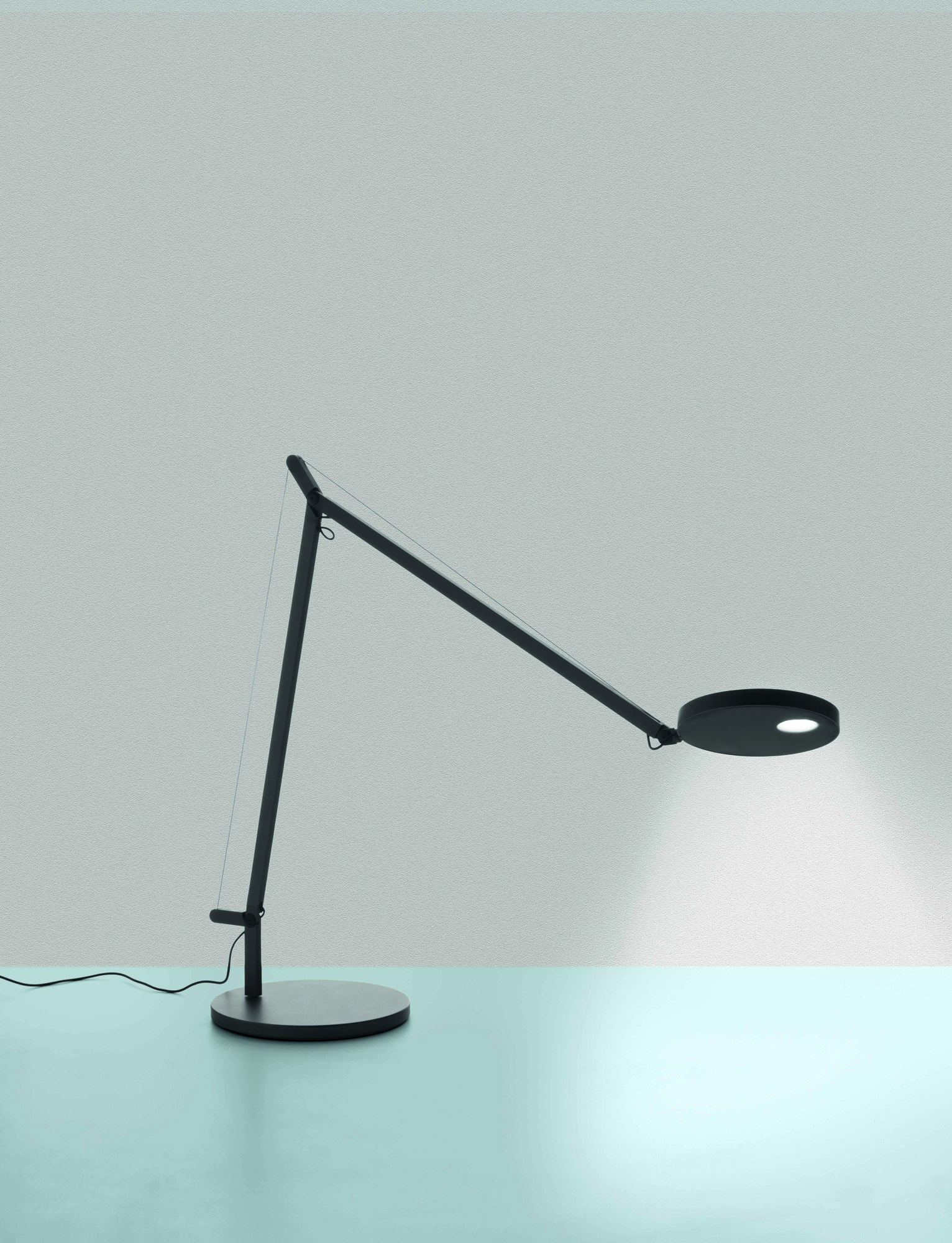 Schwarze Demetra Tischleuchte von Artemide mit verstellbarem Arm und rundem Leuchtenkopf.