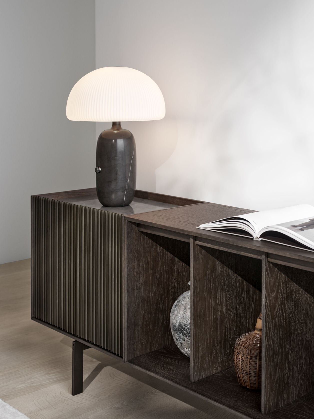 Elegantes Sideboard aus dunklem Holz mit Lampe, Buch und Deko-Objekten für stilvolles Wohnambiente.