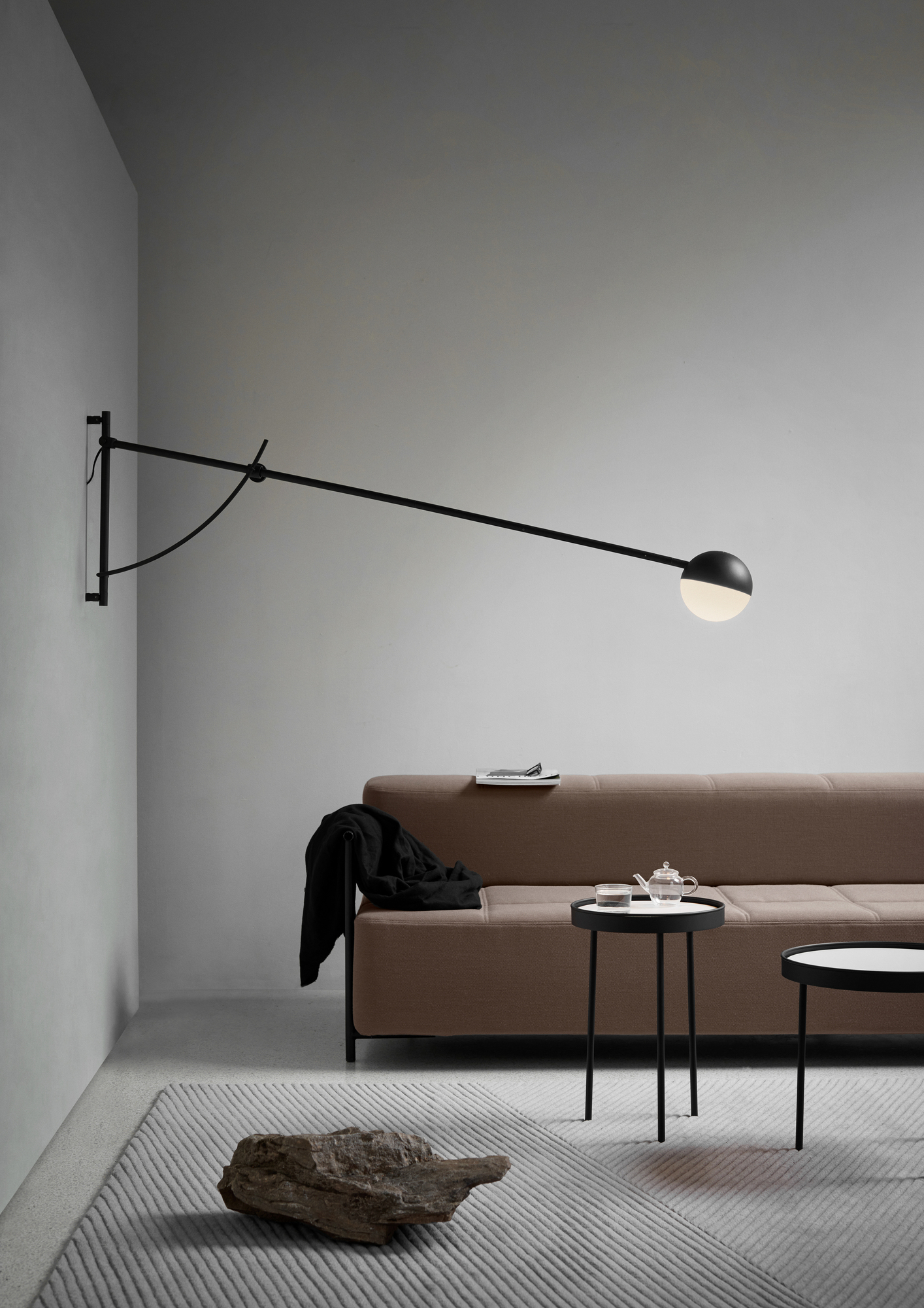 Northern Balancer Wall Wandleuchte in Schwarz über Sofa und Beistelltischen im Wohnzimmer.