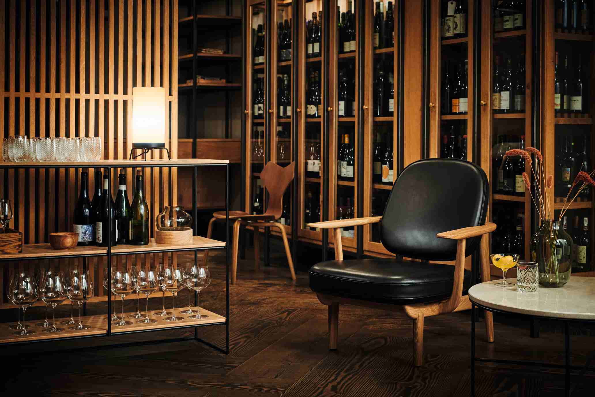 Schwarzer Fred Loungesessel von Fritz Hansen im Interieur mit Weinregal und Tisch, bequemer Design Sessel.