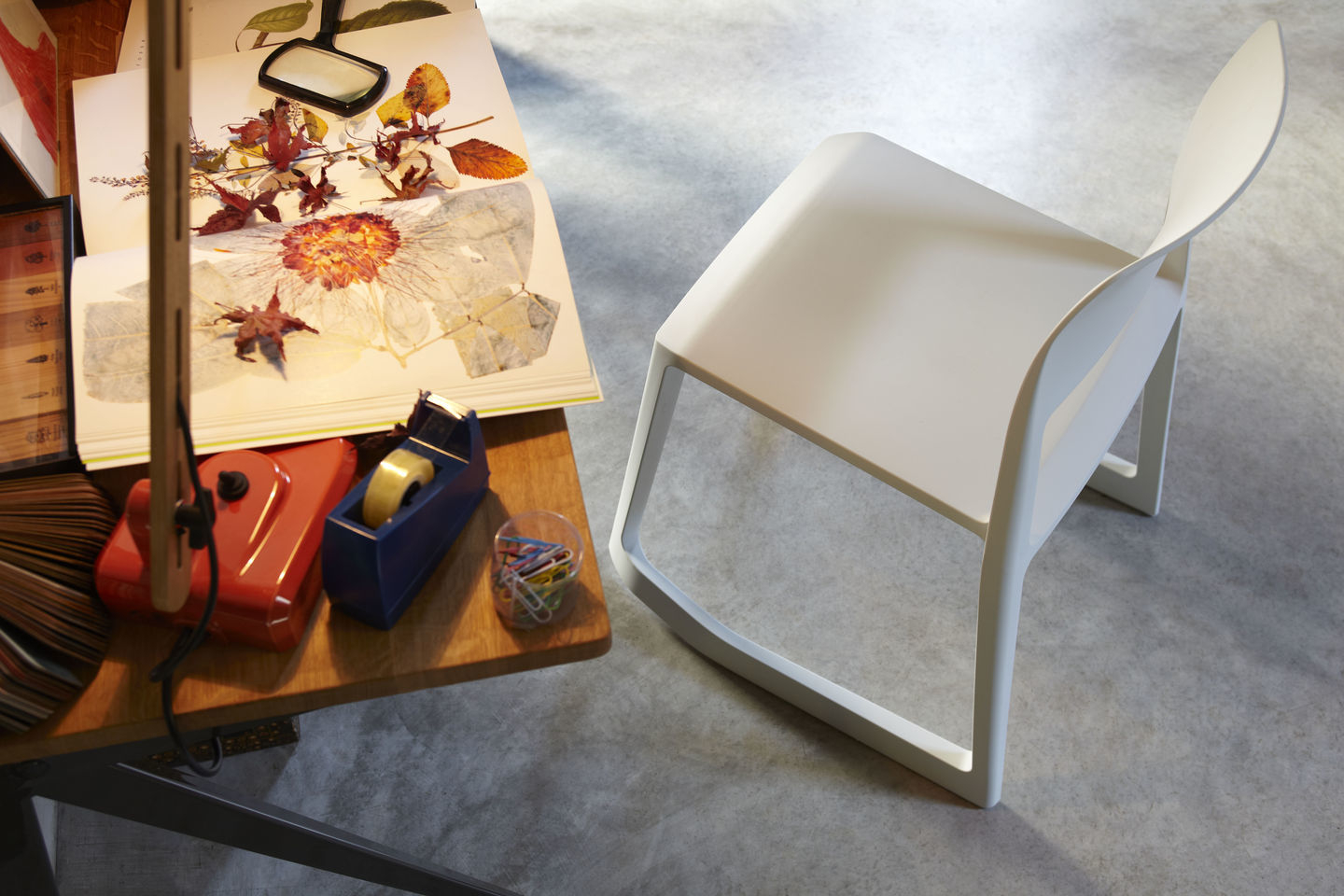 Weißer Tip Ton RE Stuhl von Vitra aus Kunststoff neben Schreibtisch mit Arbeitsmaterialien.