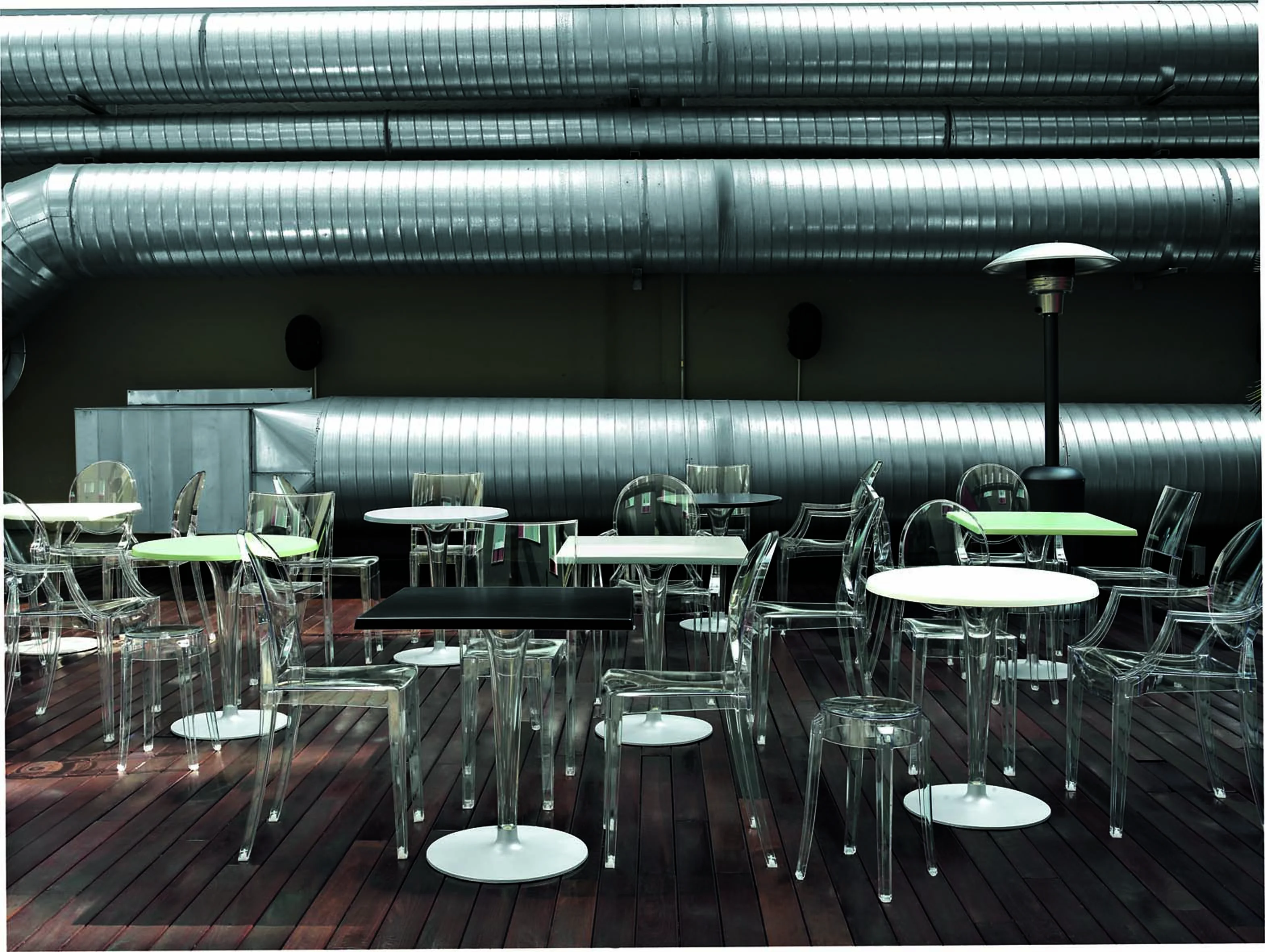 Dr. NA Tisch von Kartell: Transparente Tische und Stühle auf Holzterrasse, modernes Design für Gastronomie.
