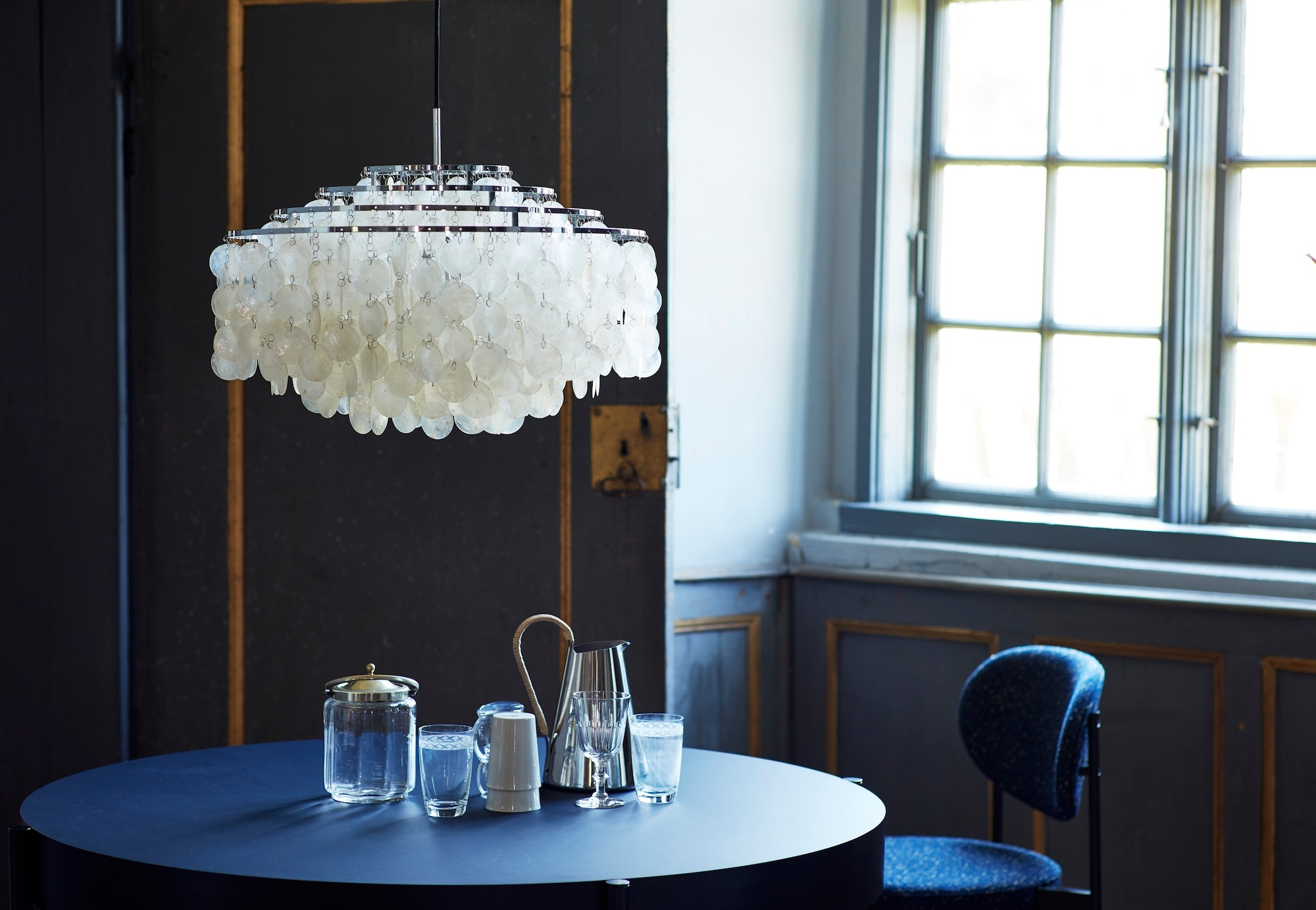 Verpan FUN Pendelleuchte mit Muscheln über blauem Tisch in einem eleganten Interieur.