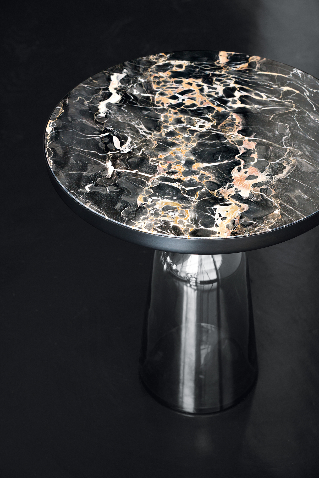 Nahaufnahme: ClassiCon Bell Coffee Table Couchtisch mit runder Tischplatte aus schwarzem Marmor mit auffälliger Maserung.