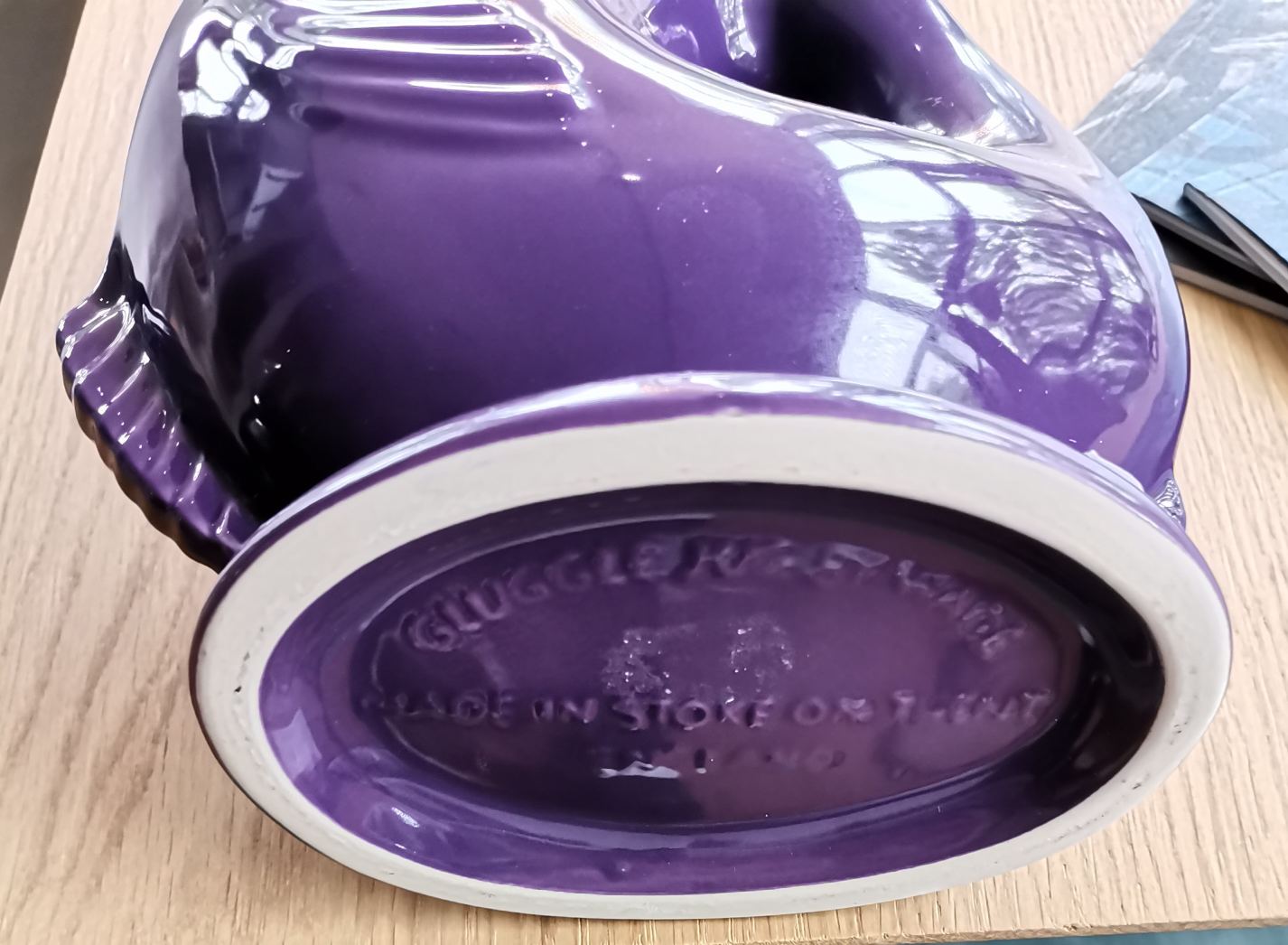 Nahaufnahme der Unterseite einer lila Gluckigluck Karaffe, Keramikvase mit Prägung "Gluggle Jug Ware".