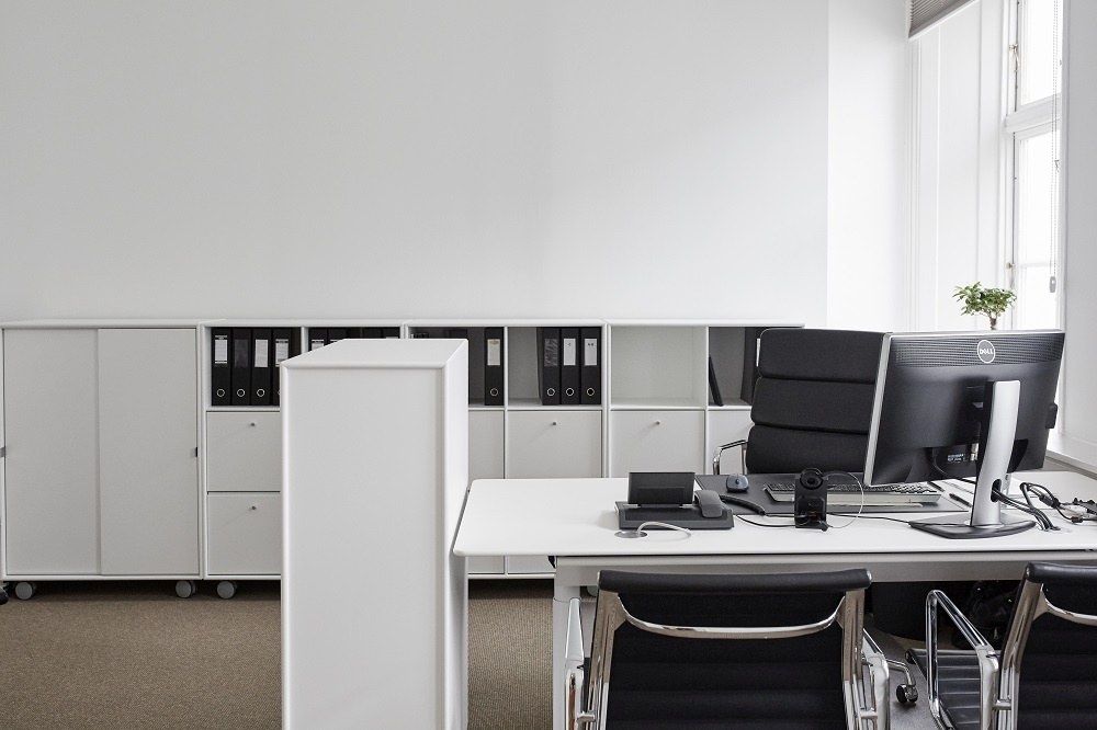Modernes Büro mit weißem Montana Cargo Modul 80 Schrank-System, Schreibtisch und Bürostuhl für stilvolle Arbeitsplatzorganisation.