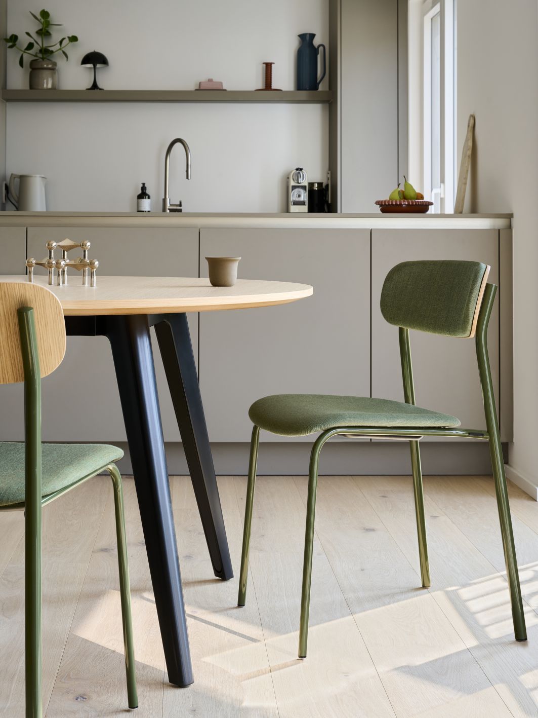 S 243 SPV Thonet Stuhl: Stahlrohrstuhl mit grüner Polsterung und Holzelementen am Esstisch.