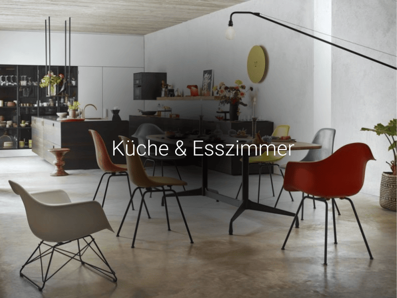 Helle Küche und Esszimmer mit Designstühlen in Weiß, Rot, Gelb und Braun um einen Esstisch.