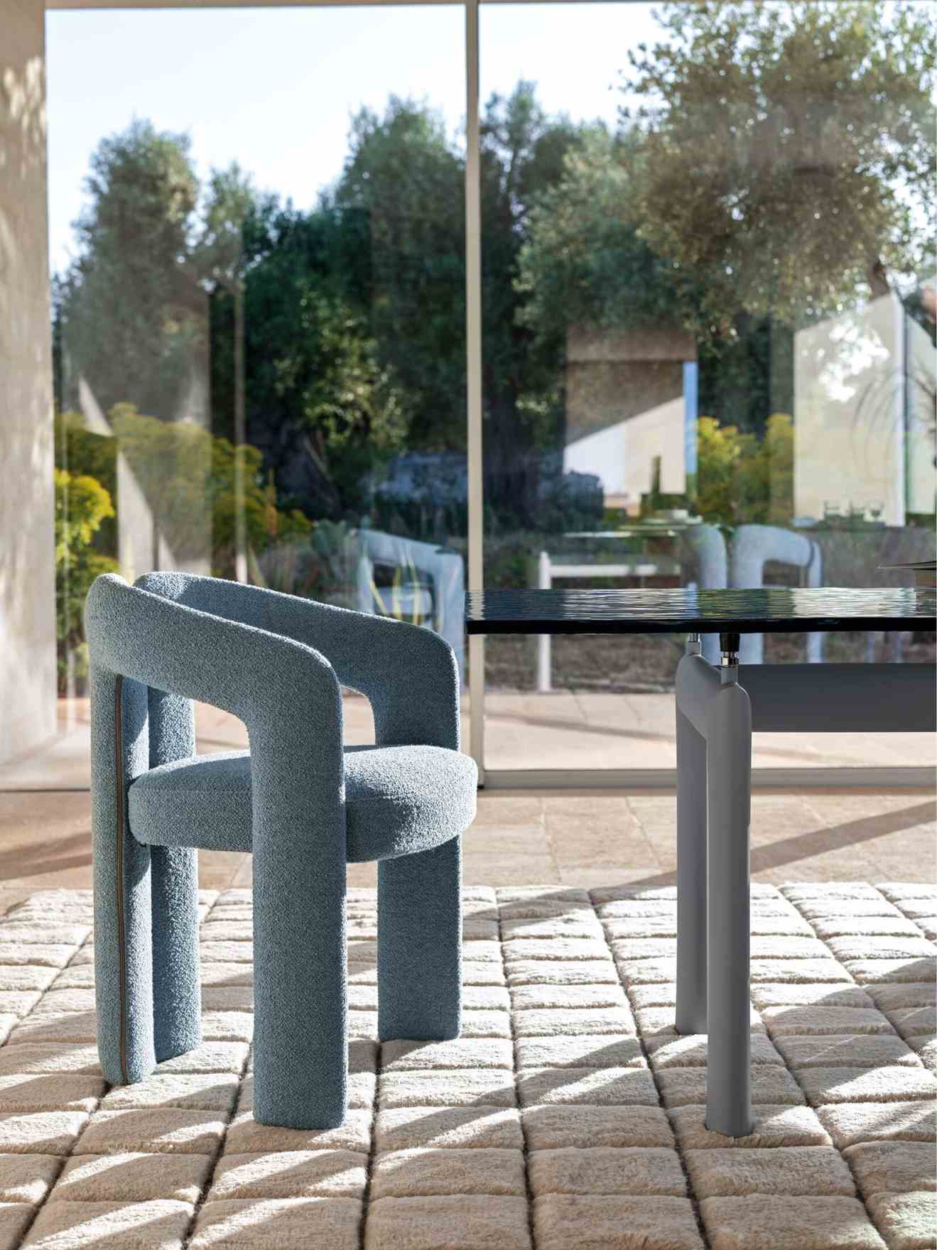 Blauer 562 Dudet Sessel von Cassina mit Bouclé-Bezug neben einem Esstisch in modernem Interieur.