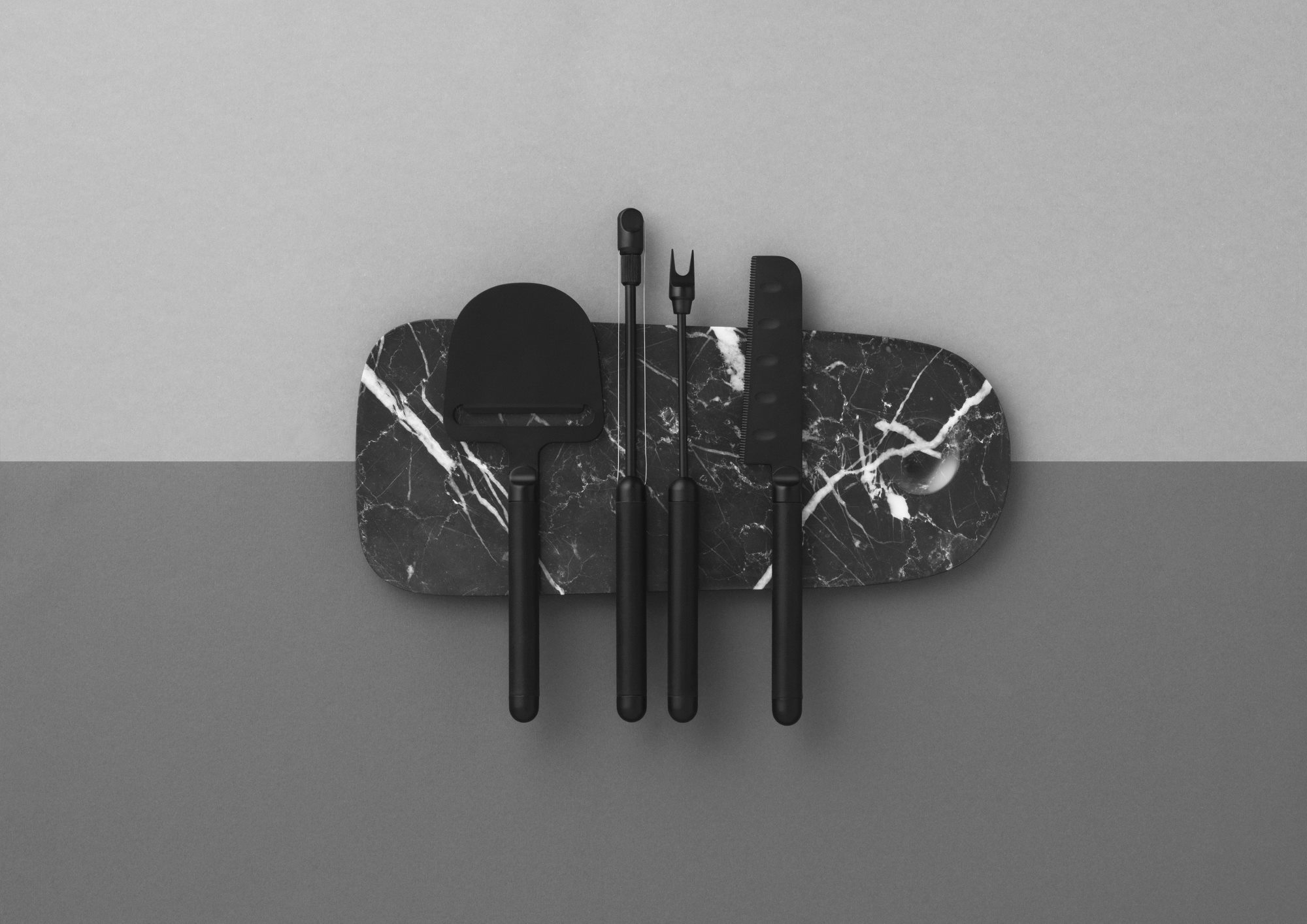 Pebble Board von Normann Copenhagen mit Käsemesser und Käsegabel auf einer Marmor Servierplatte.