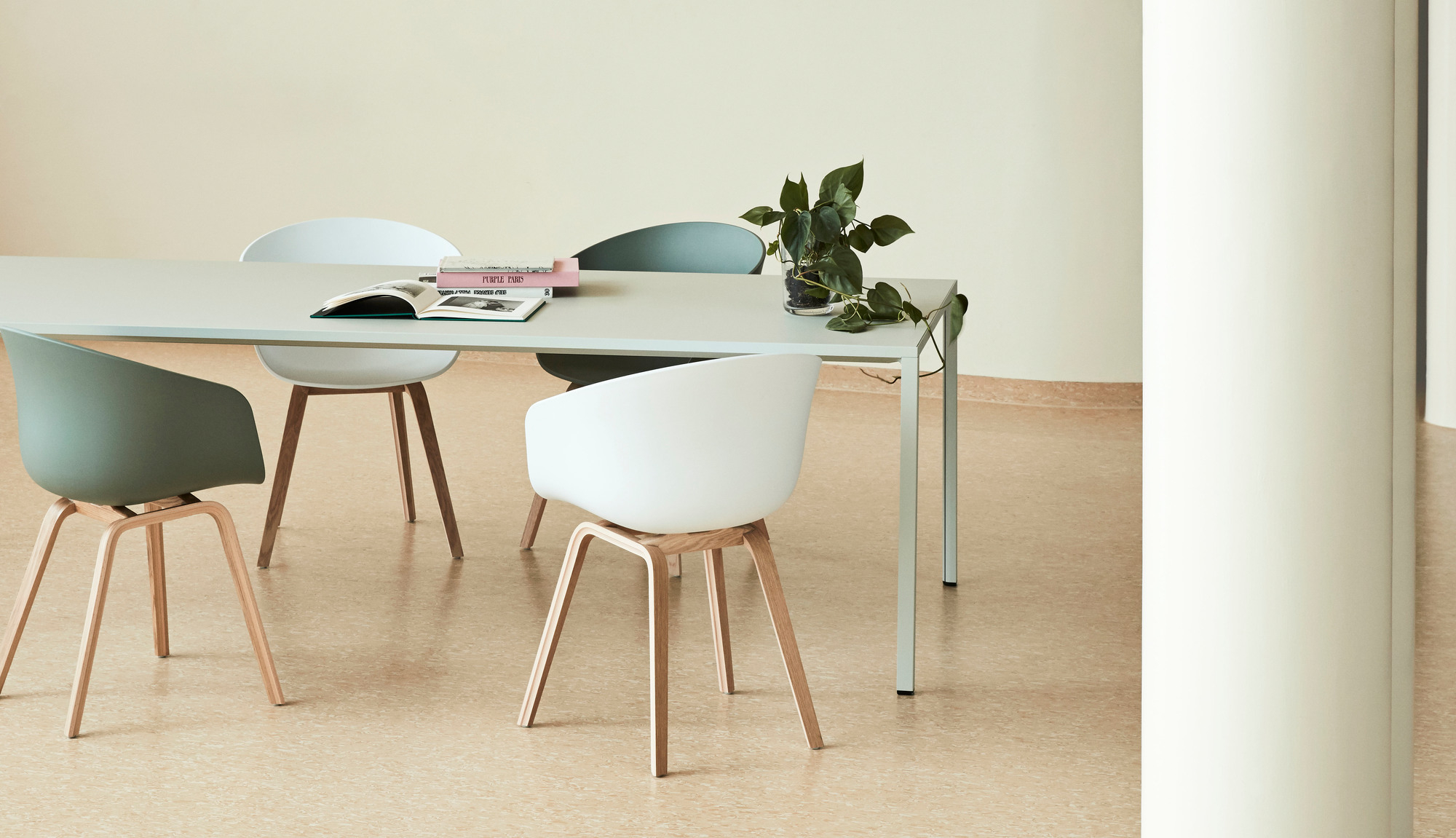 Mehrere About A Chair AAC 22 Stühle von Hay in Weiß und Grün um einen Tisch.