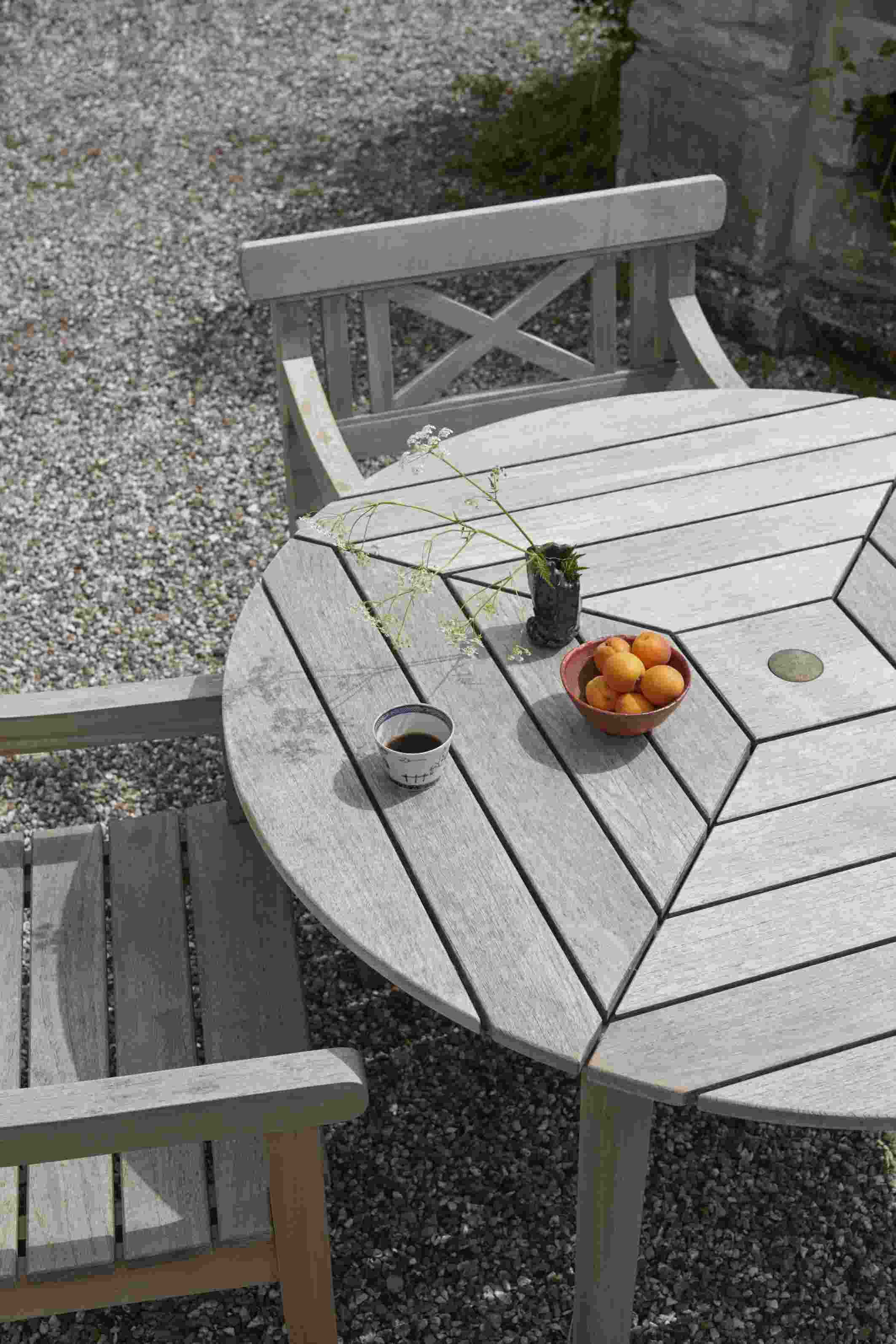 Drachmann Tisch von Skagerak by Fritz Hansen, runder Gartentisch aus Teakholz mit Stuhl und Dekoration.