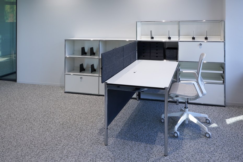 USM Haller Büromöbel: Schreibtisch mit Privacy Panels und Rollcontainer in modernem Büro.