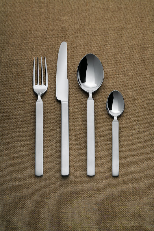 Alessi Dry Besteckset: Messer, Gabel, Esslöffel und Teelöffel aus Edelstahl auf braunem Stoffhintergrund.