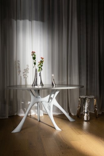 Plopp Hocker Limited Edition aus Metall neben Esstisch mit weißem Gestell und Dekoration.