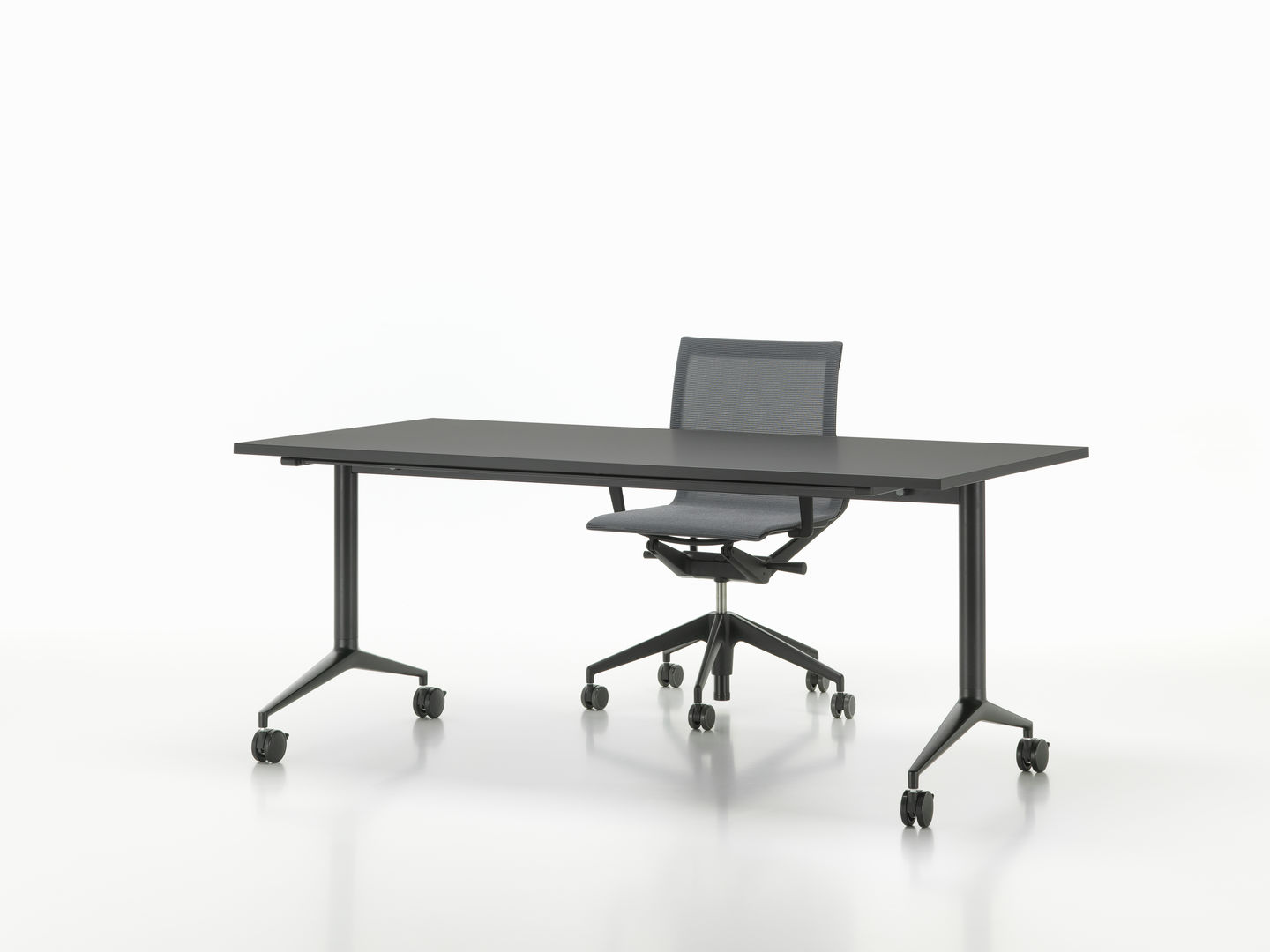 Vitra MedaMorph Klapptisch in Schwarz mit Bürostuhl auf Rollen vor weißem Hintergrund.
