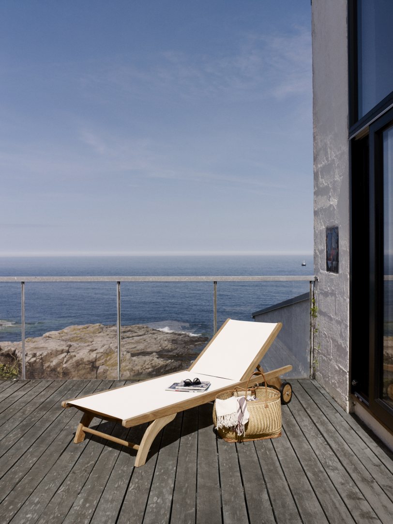 Columbus Sonnenliege von Skagerak by Fritz Hansen auf Holzterrasse mit Meerblick. Outdoor Liege aus Teakholz.
