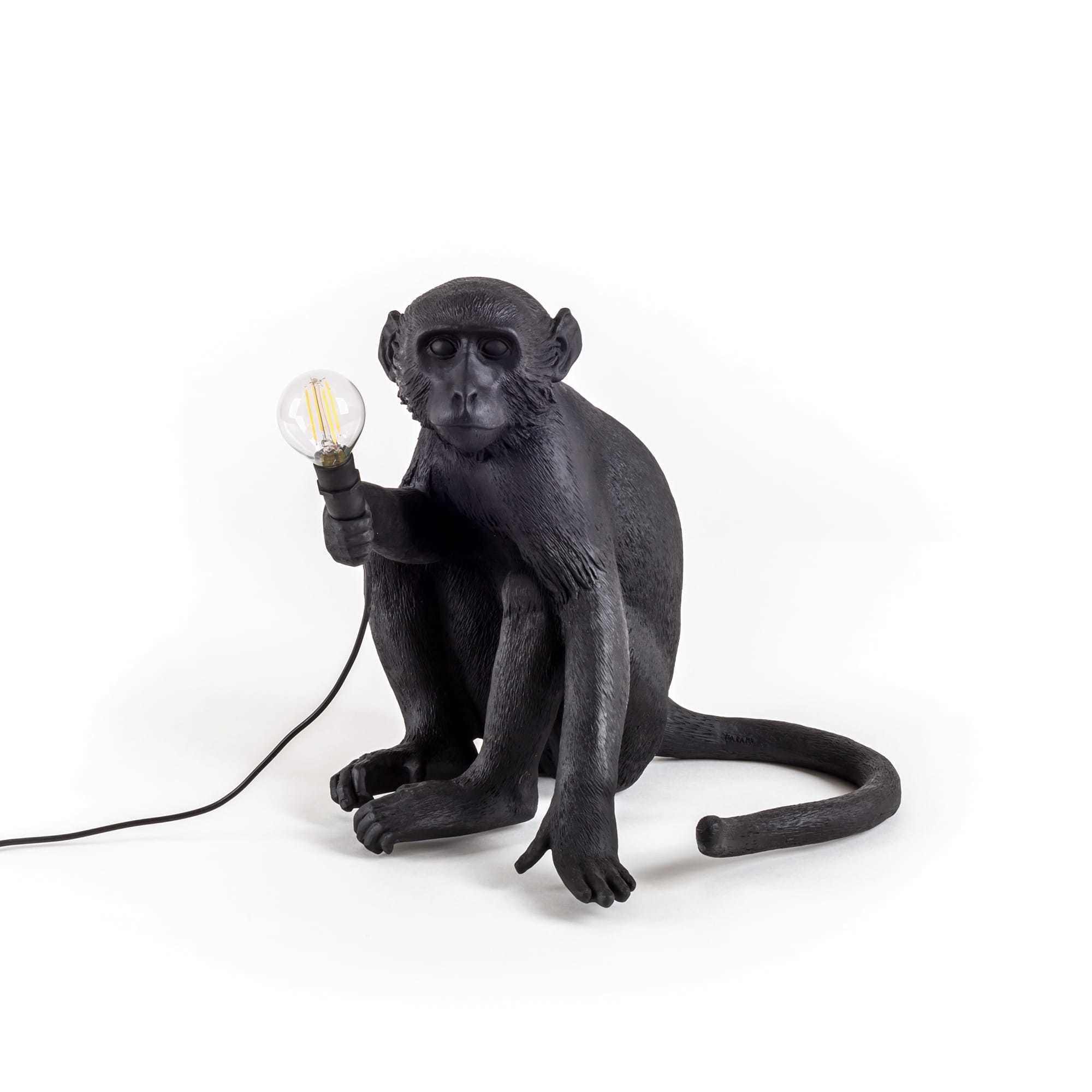 Schwarze Seletti Affenlampe, sitzend, hält eine Glühbirne. Dekorative Tischleuchte für Innen und Außen.