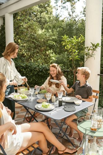 Familie genießt Mahlzeit am grauen Fermob Bistro Tisch im Freien auf der Terrasse.