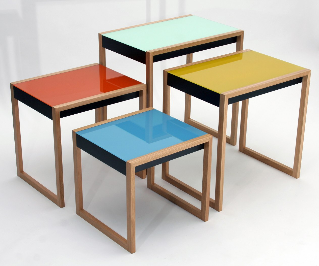 Bauhaus Satztische 4er Set von Klein & More mit farbigen Glasplatten in Orange, Gelb, Blau und Grün.