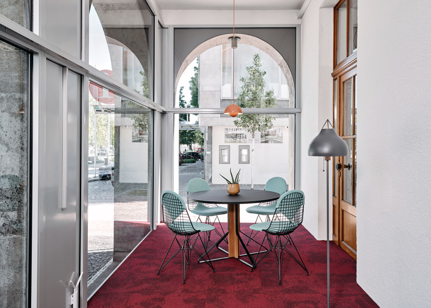 Vitra DKR Wire Chair Stühle mit mintgrünen Sitzpolstern um einen runden Esstisch.