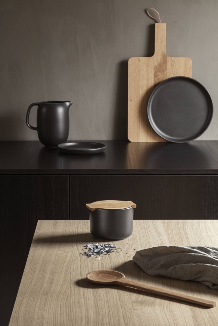 Produktfoto: Schwarzes Keramik Geschirr Set mit Holzlöffel und Schneidebrett für Küche und Tisch.