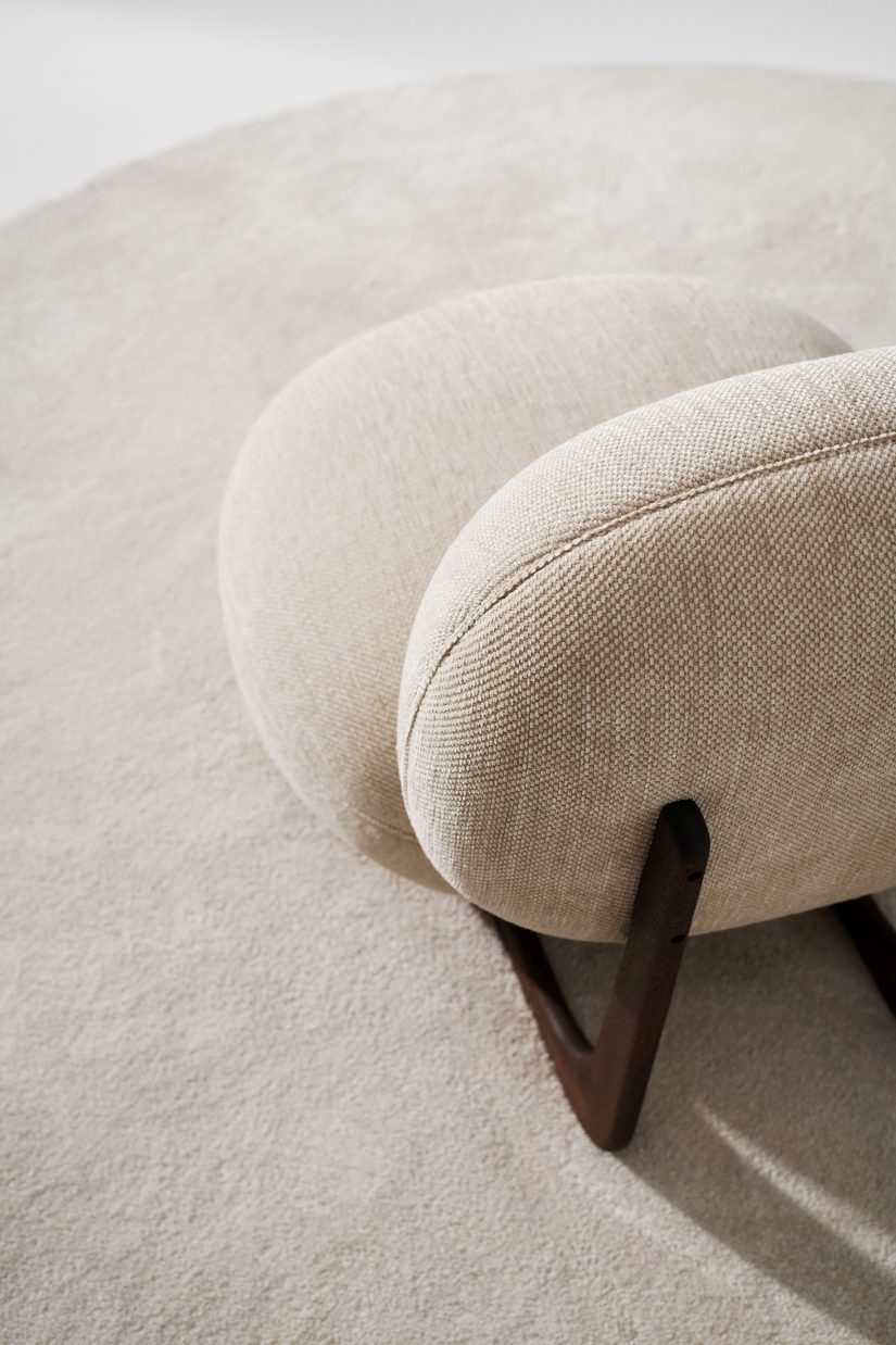 Detailaufnahme vom Copper Lounge Chair Sessel von NORR11 mit hellem Stoffbezug und dunklem Holzgestell.