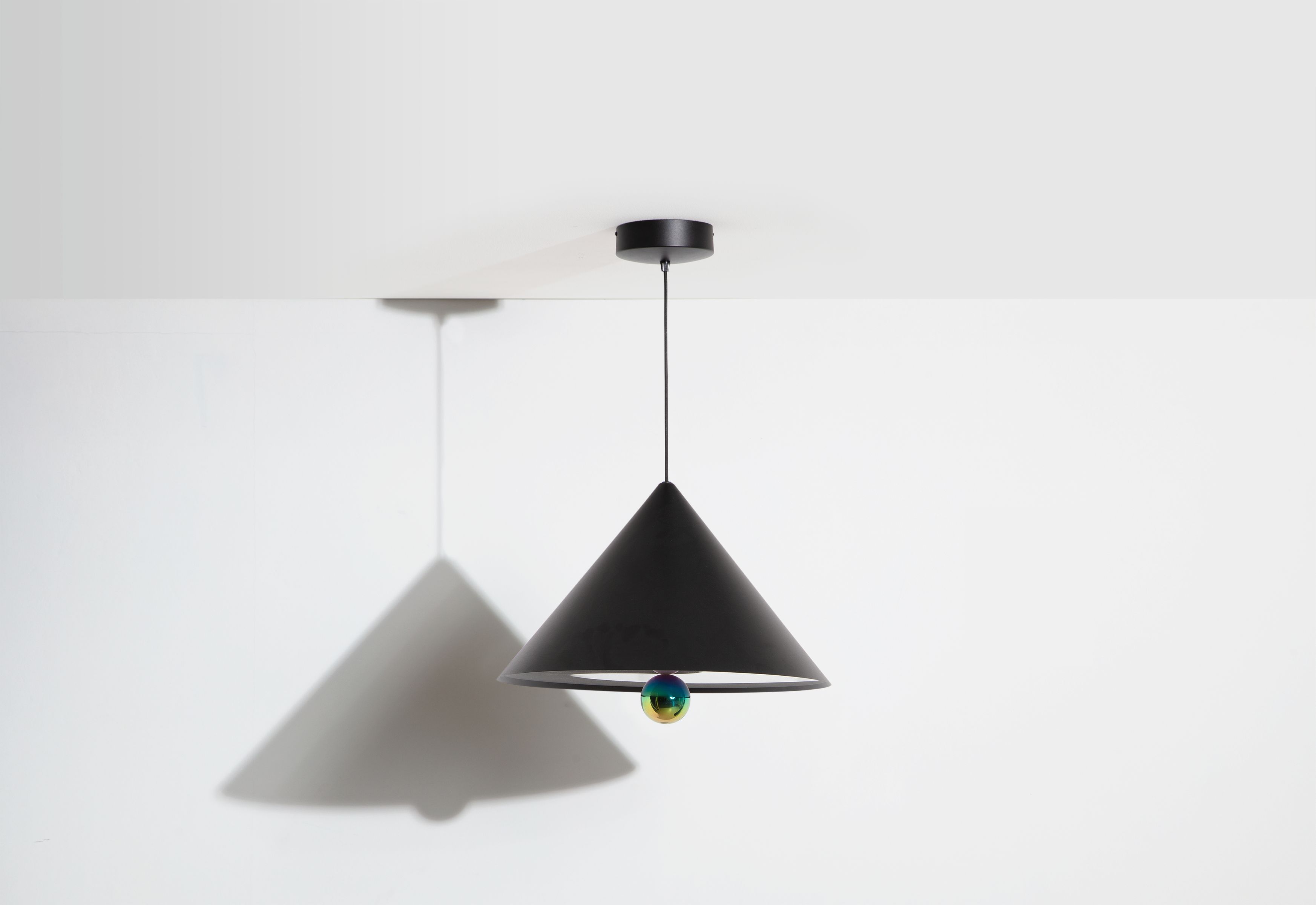 Schwarze Cherry Pendelleuchte von Petite Friture mit schimmernder Kugel und Kegelform vor weißem Hintergrund.