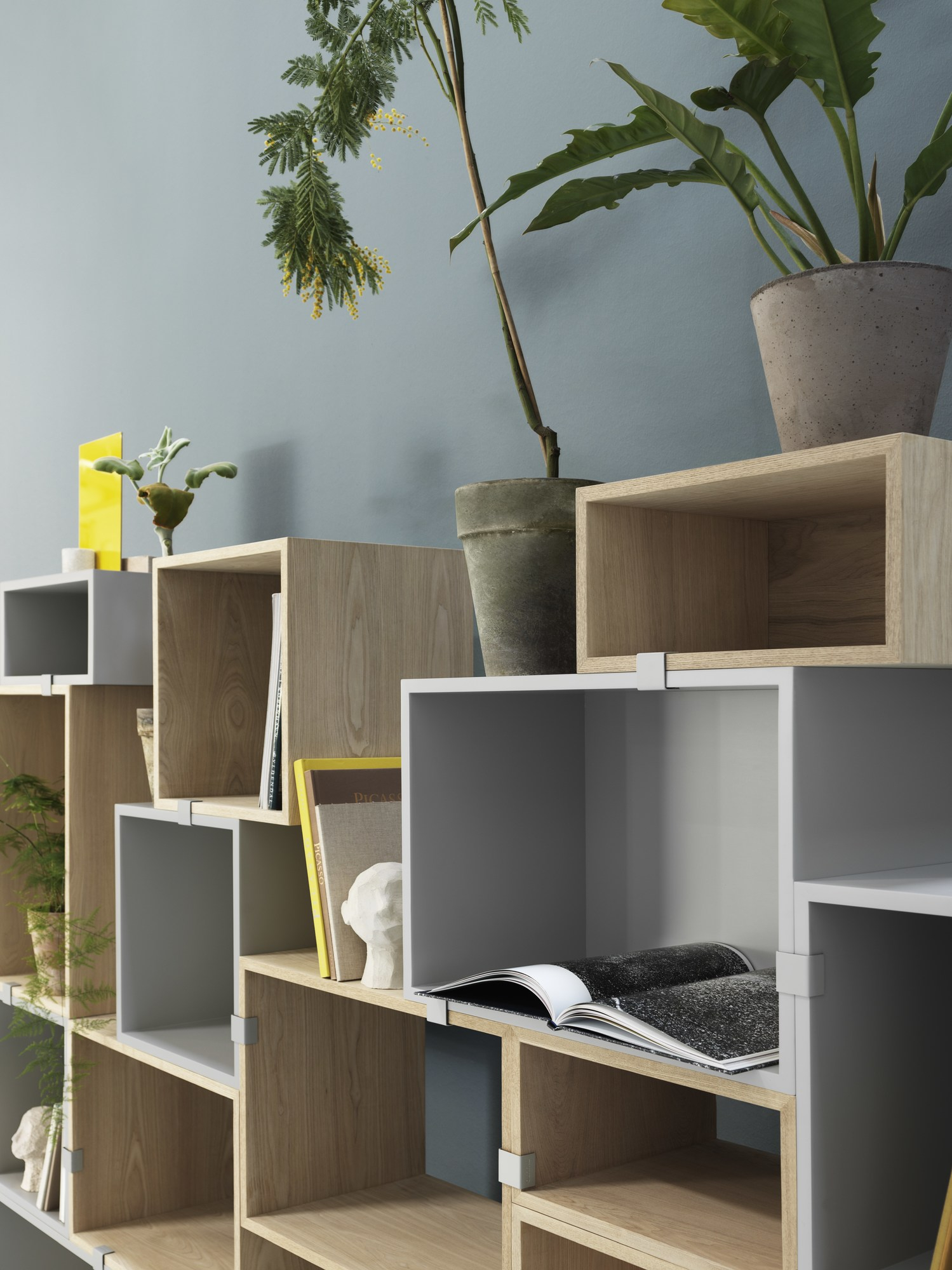 Muuto Stacked Storage System 2.0 Regalsystem aus grauen und hellbraunen Modulen mit Pflanzen und Deko.