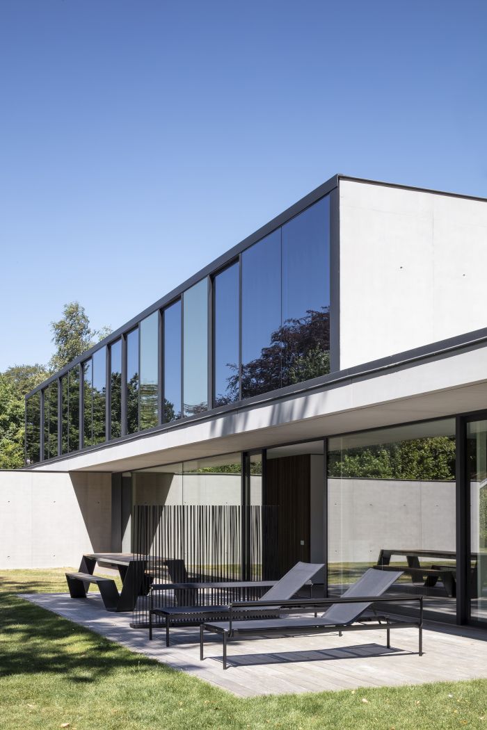 Sol + Luna Sonnenliege von Extremis im Garten eines modernen Hauses mit großen Fensterfronten.