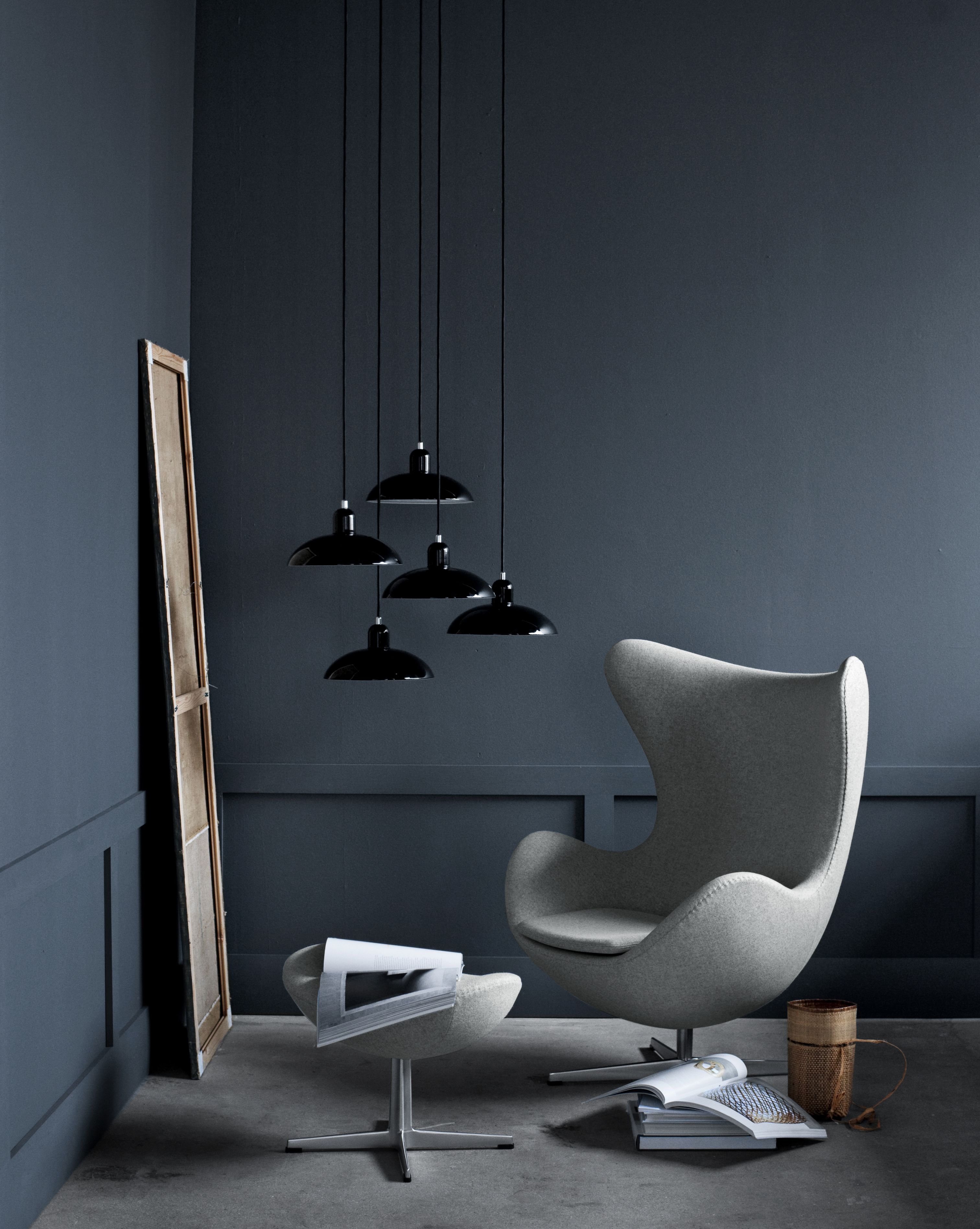 Grauer Egg Chair Sessel mit Hocker von Fritz Hansen und schwarzen Pendelleuchten im modernen Wohnzimmer.
