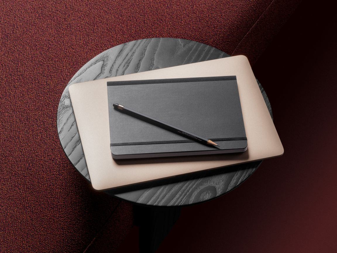 Ansicht von oben auf einen runden, schwarzen Anagram Beistelltisch von Vitra mit Laptop, Notizbuch und Bleistift.