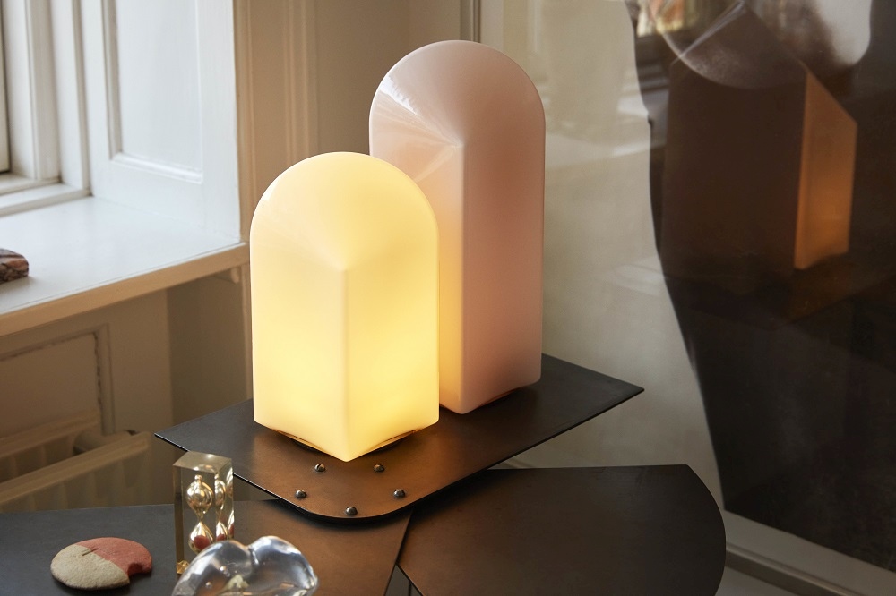 Zwei moderne Hay Parade Tischleuchten in Gelb und Rosa auf einem dunklen Metalltisch.