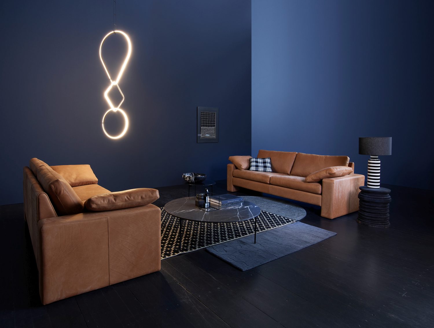Helles Conseta Ledersofa und Sessel in modernem Wohnzimmer mit blauen Wänden und Designelementen.