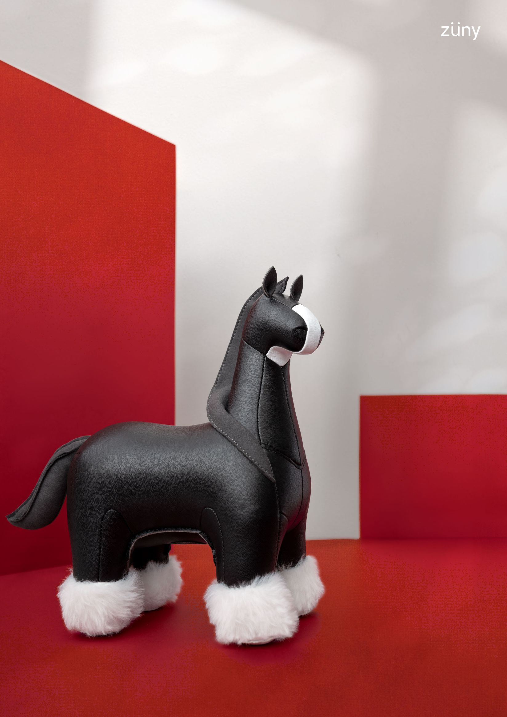 Schwarzer Züny Shire Pferd Briefbeschwerer aus Kunstleder mit weißen Akzenten und flauschigen Hufen.